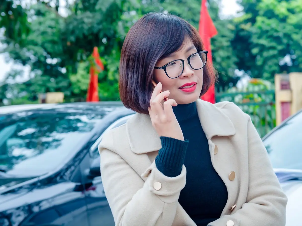 A professional on a phone call next to parked cars outside an office