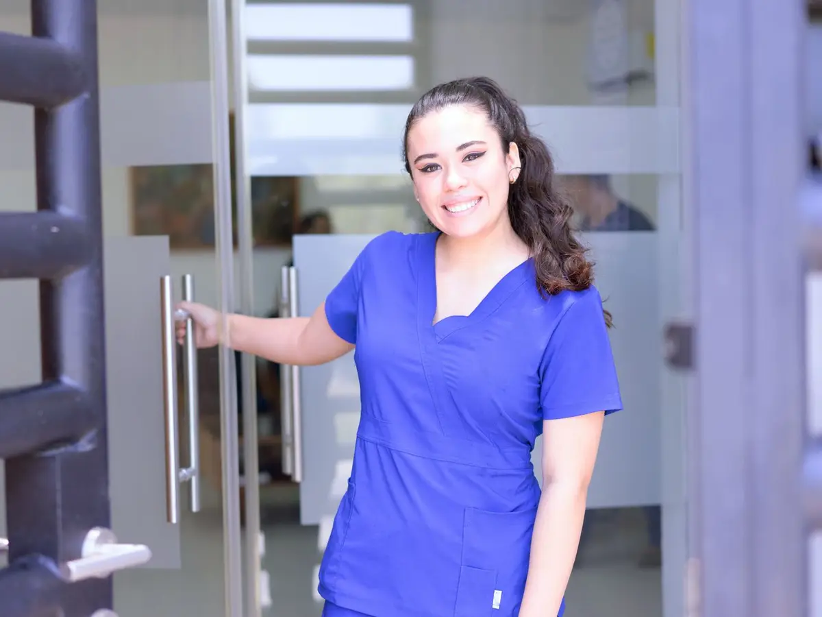 A smiling healthcare worker opening a clinic door